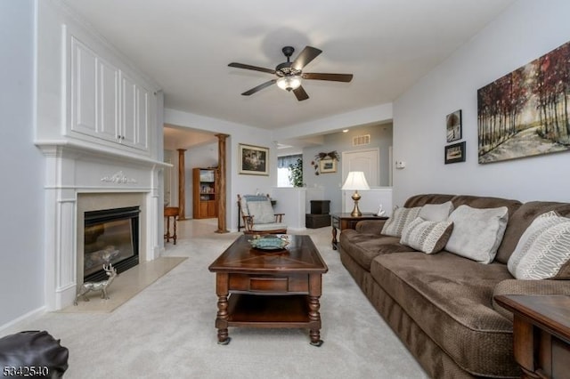 living area with light carpet, ceiling fan, and a high end fireplace