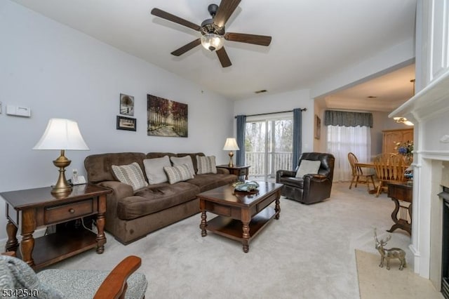 carpeted living area with a ceiling fan, lofted ceiling, a fireplace, and visible vents