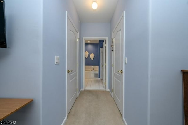 corridor with light colored carpet, visible vents, and baseboards