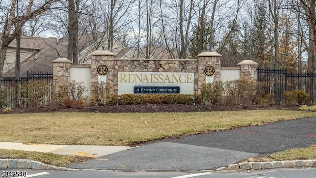 community / neighborhood sign with a yard and fence