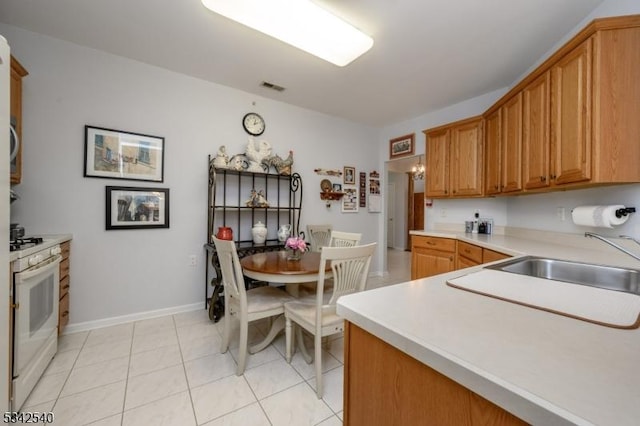 kitchen featuring visible vents, a sink, light countertops, light tile patterned floors, and white gas range