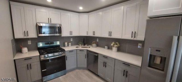 kitchen featuring light countertops, appliances with stainless steel finishes, a sink, and decorative backsplash