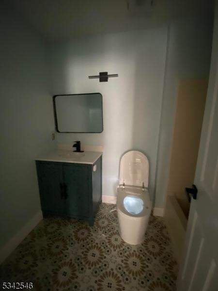 bathroom featuring toilet, baseboards, speckled floor, and vanity