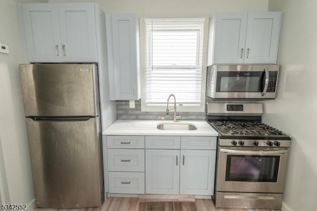 kitchen with stainless steel appliances, light wood-style flooring, a sink, and light countertops