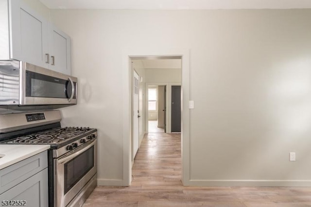 kitchen featuring light countertops, appliances with stainless steel finishes, light wood-type flooring, and baseboards