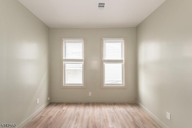 spare room with light wood-style floors, baseboards, and visible vents