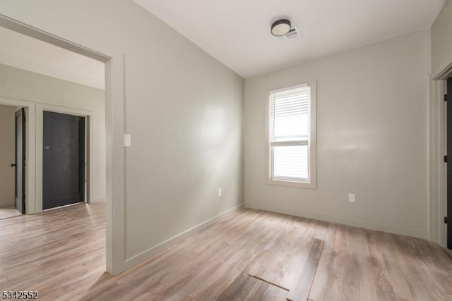 spare room with light wood-type flooring, visible vents, and baseboards