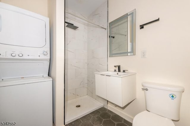 full bath featuring stacked washer and clothes dryer, toilet, vanity, tile patterned flooring, and tiled shower