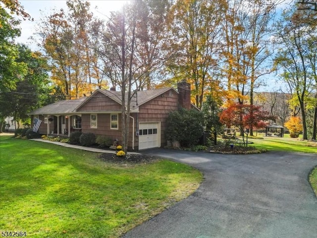 exterior space with a lawn, a garage, driveway, and a chimney