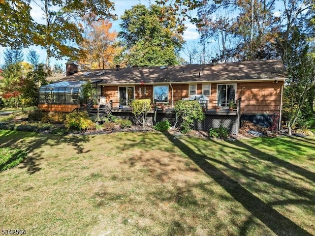 back of house featuring a wooden deck, a lawn, a chimney, and a sunroom