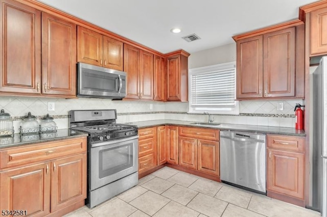 kitchen featuring light tile patterned flooring, stainless steel appliances, a sink, visible vents, and decorative backsplash