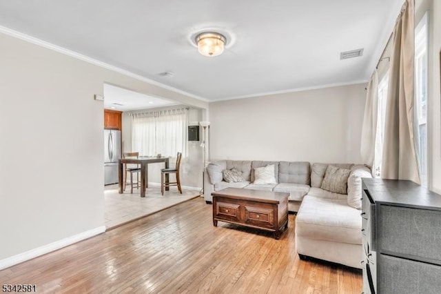 living area featuring ornamental molding, visible vents, light wood-style flooring, and baseboards