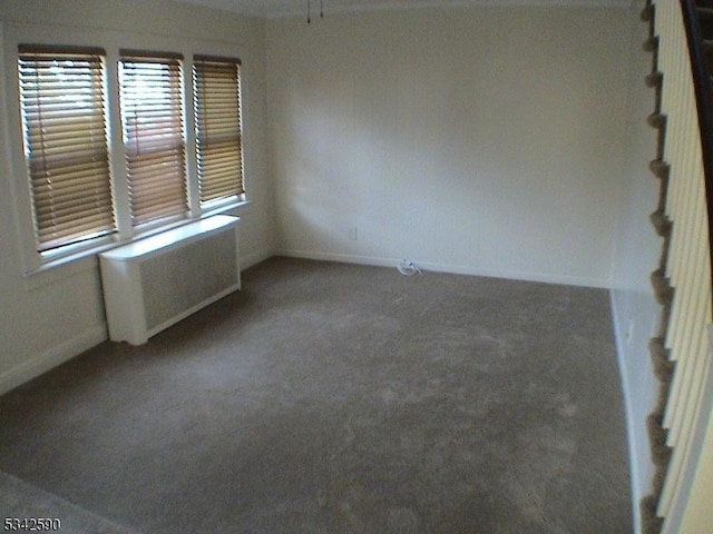 carpeted empty room featuring radiator and baseboards