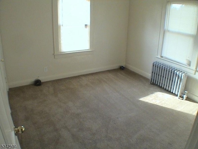 carpeted spare room with radiator and baseboards