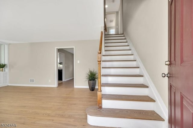 staircase featuring wood finished floors, visible vents, and baseboards