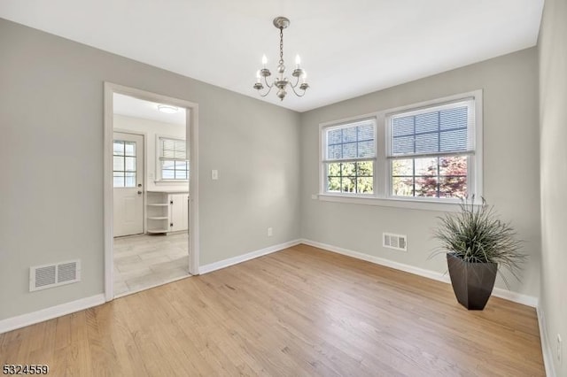 unfurnished room with light wood-style floors, plenty of natural light, and visible vents