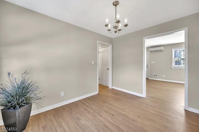 unfurnished room with baseboards, visible vents, light wood-style floors, a notable chandelier, and a wall mounted AC