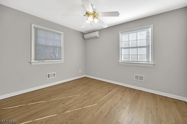 spare room featuring baseboards, visible vents, wood finished floors, and a wall mounted air conditioner