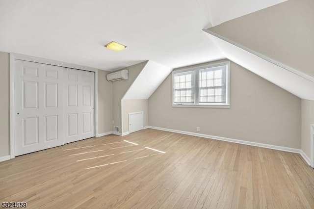 bonus room with light wood finished floors, visible vents, a wall mounted AC, vaulted ceiling, and baseboards