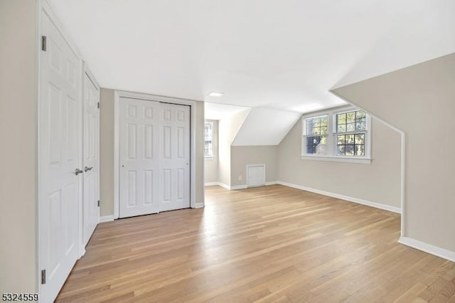 additional living space featuring lofted ceiling, light wood-style flooring, and baseboards