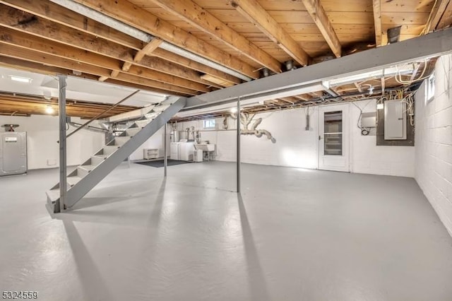 below grade area featuring a sink, stairs, water heater, independent washer and dryer, and electric panel