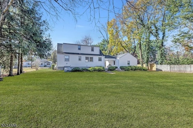 rear view of property featuring fence and a lawn