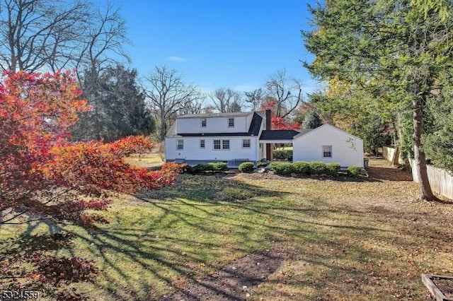 rear view of property featuring a lawn and a chimney