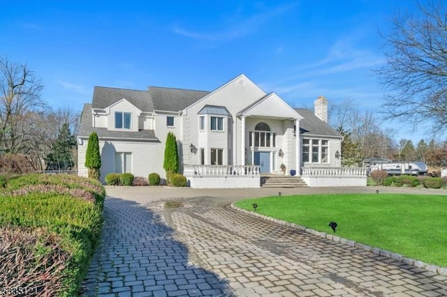 view of front facade featuring a chimney and a front lawn