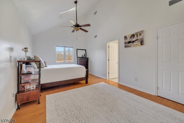 bedroom featuring high vaulted ceiling, light wood-style flooring, visible vents, and baseboards