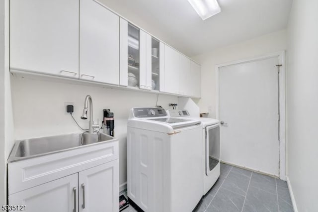 laundry area with independent washer and dryer, a sink, and cabinet space