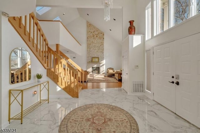 entryway featuring marble finish floor, visible vents, a large fireplace, and stairway