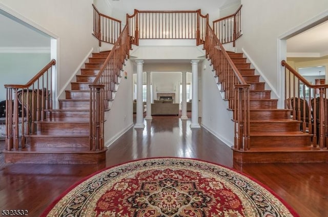 foyer entrance with baseboards, wood finished floors, decorative columns, and crown molding