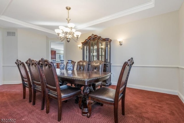 carpeted dining room featuring baseboards, ornamental molding, visible vents, and an inviting chandelier