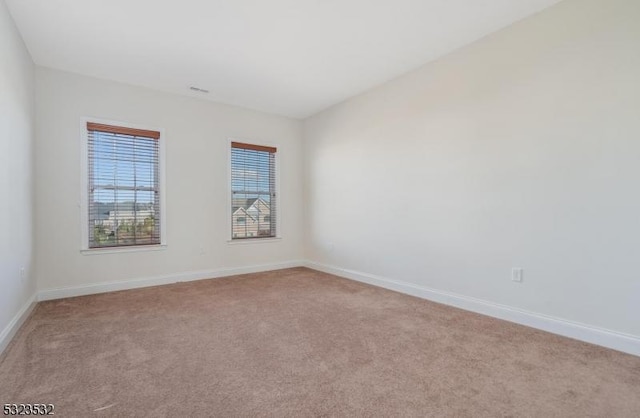 empty room featuring baseboards and light colored carpet