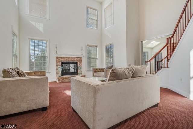 living room featuring baseboards, a towering ceiling, stairway, dark colored carpet, and a fireplace