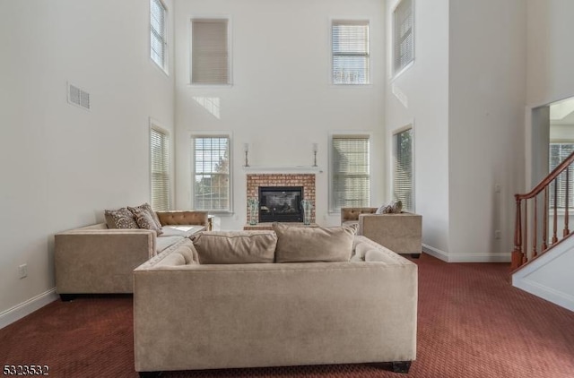 living room with dark carpet, a fireplace, visible vents, and a healthy amount of sunlight