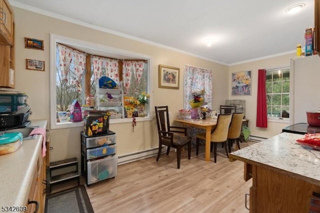 dining room with a baseboard heating unit, light wood-style floors, and crown molding