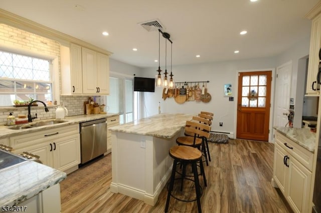 kitchen featuring a kitchen breakfast bar, dishwasher, a sink, and wood finished floors