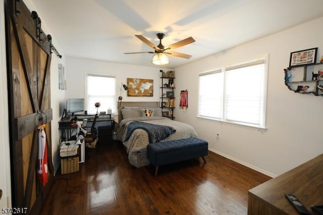 bedroom with a ceiling fan, a barn door, baseboards, and wood finished floors