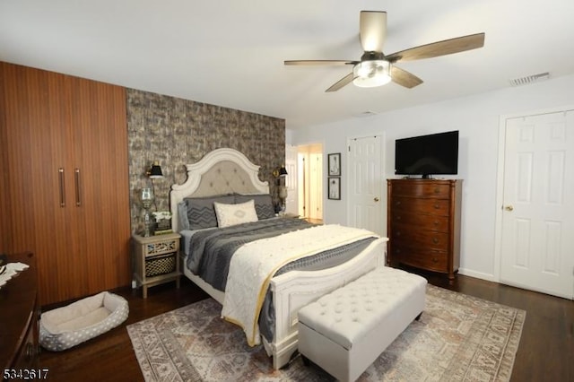 bedroom featuring ceiling fan, wood finished floors, visible vents, and baseboards