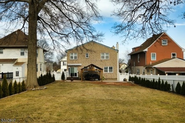 rear view of house featuring a yard, a chimney, and a fenced backyard