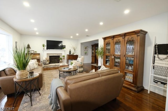 living area with dark wood-type flooring, a fireplace, and recessed lighting