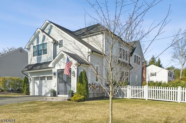 view of front facade with aphalt driveway, a garage, a front yard, and fence