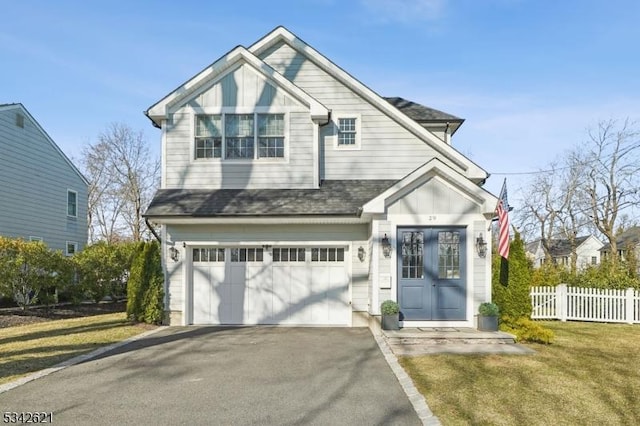 view of front of house with a front yard, fence, driveway, roof with shingles, and an attached garage