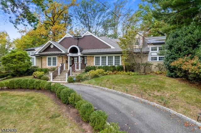 view of front of home with stone siding and a front lawn