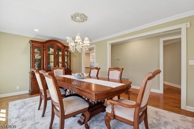 dining area with light wood-style floors, baseboards, crown molding, and an inviting chandelier