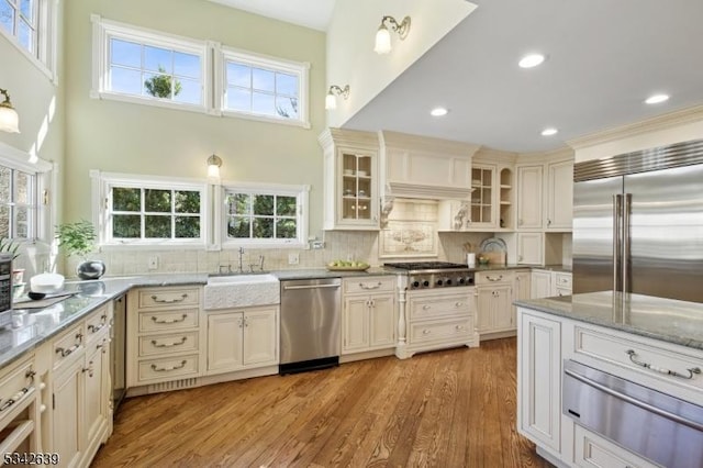 kitchen featuring a warming drawer, light stone counters, a sink, tasteful backsplash, and appliances with stainless steel finishes