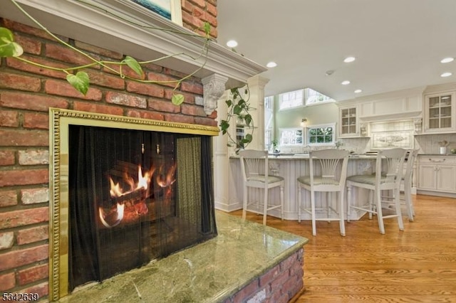 details with tasteful backsplash, recessed lighting, a lit fireplace, and wood finished floors