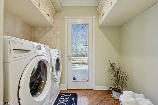 clothes washing area with crown molding, baseboards, light wood-type flooring, cabinet space, and separate washer and dryer