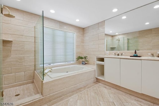 bathroom with a shower stall, double vanity, a bath, tile walls, and a sink